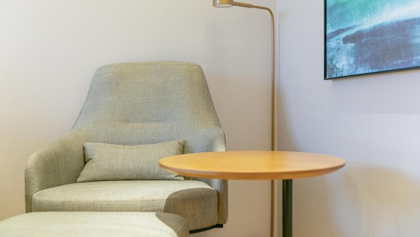 A room with a light-colored armchair, a small round table, and a floor lamp. - Ji Hotel (Luoyang)
