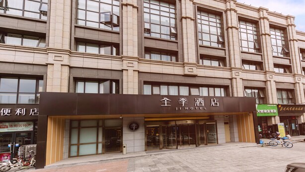 Un hotel con una entrada destacada, amplias ventanas y un cartel que indica que es un hotel.