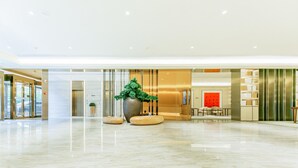 A spacious lobby with a marble floor, a reception desk, and a large potted plant. - Ji Hotel (Luoyang)