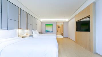A hotel room with two beds, a TV, and a hallway leading to another room.