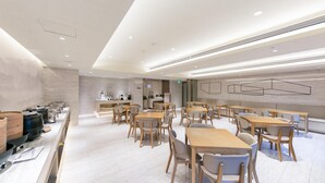 A modern dining area with wooden tables and chairs, a kitchen area with appliances, and a clean, minimalist design. - Ji Hotel (Luoyang)