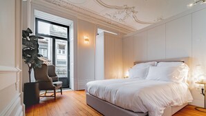 Una camera da letto con un letto grande, una sedia, una pianta e vista sull'esterno.