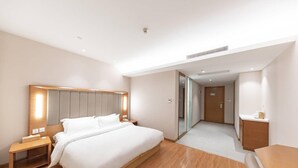 A modern hotel room with a large bed, bedside tables, a desk, and a walk-in closet. - Ji Hotel Shanghai Jiayi Road Subway Statio (Shanghai)