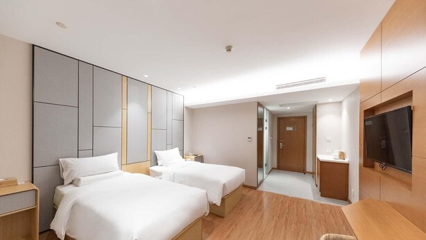 A hotel room with two beds, a desk, a TV, and a mirror. - Ji Hotel Shanghai Jiayi Road Subway Statio (Shanghai)