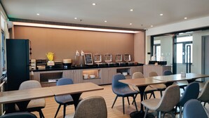 Ein moderner Konferenzraum mit einem langen Tisch, mehreren Stühlen, einer Küchenzeile und einem großen Fenster.