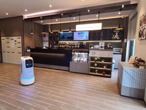 Ein modernes Café-Interieur mit einer Rezeption, digitalen Menütafeln und einem Selbstbedienungsgetränkeautomaten.