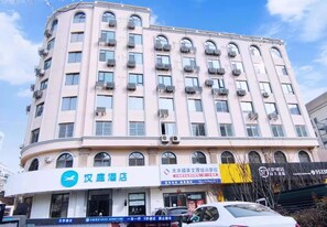 Ein mehrgeschossiges Hotel mit geschwungener Fassade, mehreren Balkonen und Hinweisschildern für ein Hotel und eine Fachschule.