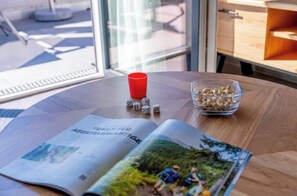 A magazine on a table with dice and a bowl of snacks. - Stay | T9 3-room sky loft (Titisee-Neustadt)