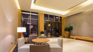 A hotel lobby with seating, a lamp, large windows, and a plant. - Ji Hotel (Chengdu)