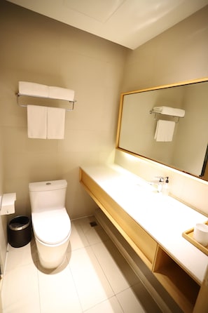 A bathroom with a toilet, a sink, a mirror, and a towel rack. - Ji Hotel (Chengdu)