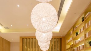 A conference room with a long wooden table, chairs, a modern chandelier, and bookshelves. - Ji Hotel (Chengdu)