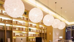 A modern library with a long wooden table, multiple chairs, and large spherical pendant lights. - Ji Hotel (Chengdu)