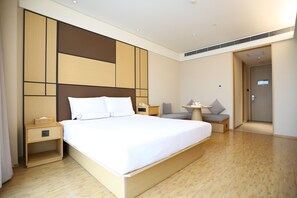 A hotel room with a large bed, bedside tables, a desk, a chair, and a small table. - Ji Hotel (Chengdu)