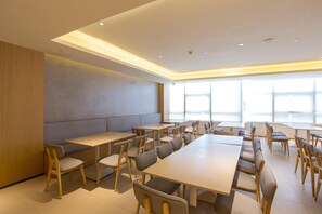 A conference room with multiple tables and chairs, large windows, and a modern ceiling design. - Ji Hotel (Chengdu)