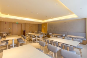 A conference room with multiple tables and chairs, a podium, and a large wall with a textured pattern. - Ji Hotel (Chengdu)