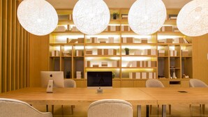 A conference room with a long table, chairs, a computer, and shelves with books and decorative items. - Ji Hotel (Chengdu)
