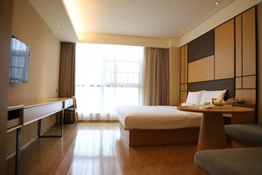 A hotel room with a bed, a desk, a chair, a small table, and a TV on the wall. - Ji Hotel (Chengdu)