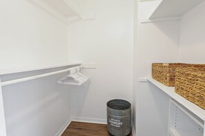 A white closet with shelves, a metal laundry can, and woven baskets. - Peaceful 2-bedroom townhome across the street from beach in N. Hutchinson Island (Fort Pierce)