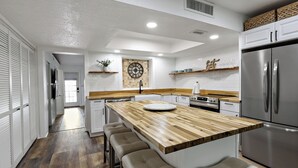 Una cocina moderna con una isla de madera, electrodomésticos de acero inoxidable y un reloj en la pared.