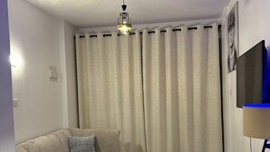A living room with a sofa, a coffee table, a TV, and a patterned rug. - Perfect 1-bedroom apartment with fitness gym in the building (Nairobi)
