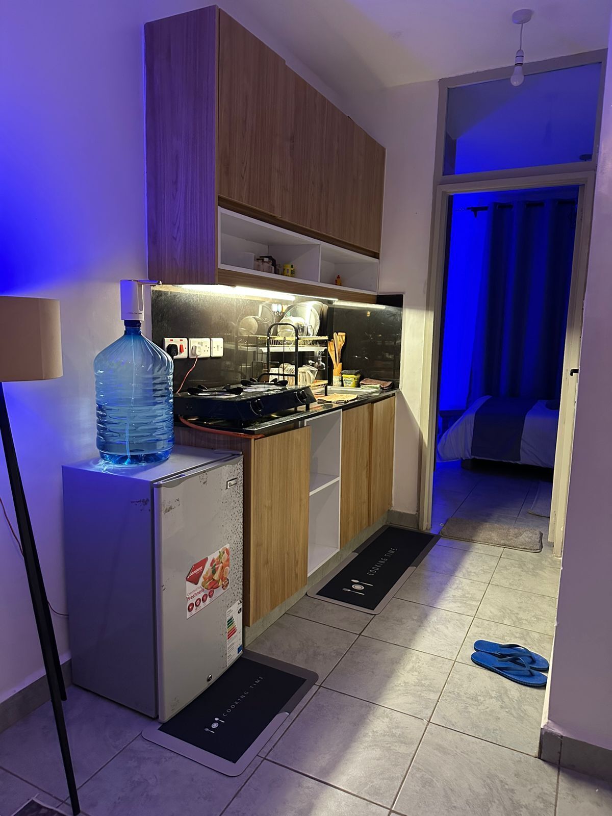Una cocina compacta con gabinetes de madera, lavavajillas integrado y dispensador de agua.