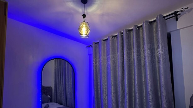 A bedroom with a bed, a mirror, and a ceiling light fixture. - Perfect 1-bedroom apartment with fitness gym in the building (Nairobi)