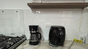 Una cucina con gas, una moka e un tostapane su un piano di lavoro piastrellato.