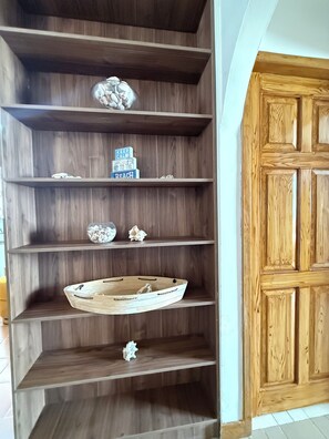 Ein Holzregal mit Dekorationselementen, eine Holztür und ein Fliesenboden.