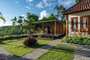 A house with a covered patio, a garden with various plants, and a view of the surrounding greenery. - Sunrise Penida Hill by ABM (Penida Island)