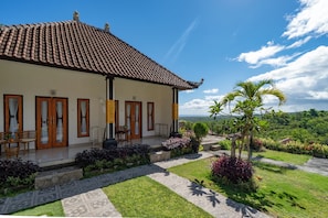A house with a tiled roof, a porch with seating, and a garden with various plants. - Sunrise Penida Hill by ABM (Penida Island)