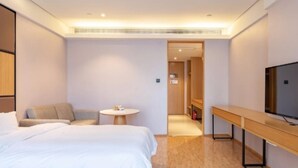 Een moderne hotelkamer met een bed, een zithoek, een tafeltje en een televisie.