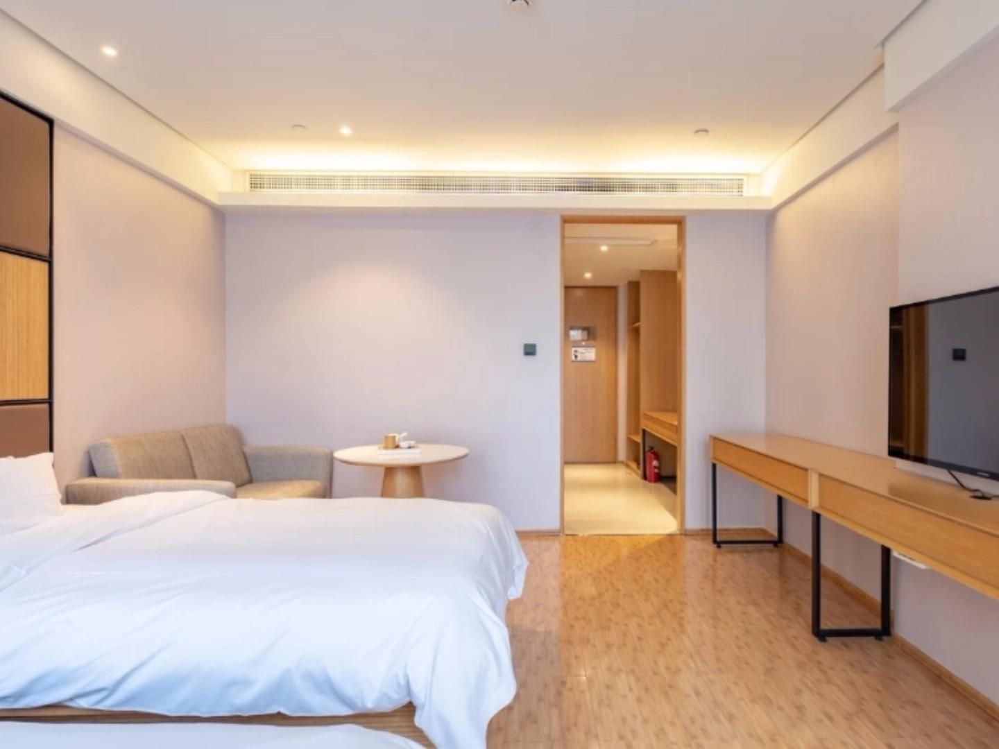 Una moderna camera d'albergo con un letto, un angolo salotto, un tavolino e una televisione.