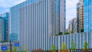 Een modern hoog gebouw met verticale lijnen, waarschijnlijk een hotel of kantoorgebouw, omringd door andere hoge gebouwen.