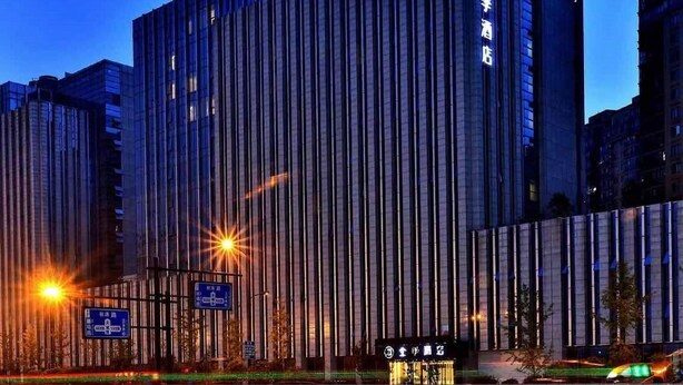 Een modern hotelgebouw met verticale lijnen, een bord dat het als hotel identificeert en een goed verlichte ingang.