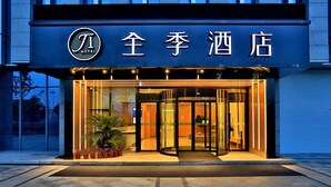 Een hotelingang met een draaideur, glazen gevel en verlichte signage.