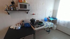 Une cuisine équipée d’un four à micro-ondes, d’une cuisinière, d’un évier et de divers ustensiles de cuisine rangés sur des étagères.