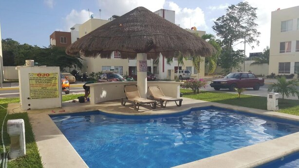 Une piscine avec des chaises longues, un parasol en chaume et un panneau indiquant une classification de trois étoiles.