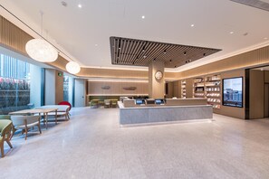 A modern hotel lobby with a reception desk, seating area, and a large window. - Ji Hotel (nanjing Xinjiekou Central Shopping Cente (Nanjing)
