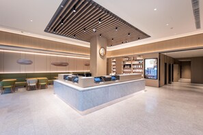 A modern hotel lobby with a reception desk, seating area, and a large digital display. - Ji Hotel (nanjing Xinjiekou Central Shopping Cente (Nanjing)