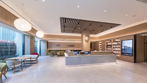 En moderne hotellobby med reception, siddeområde og et stort vindue.