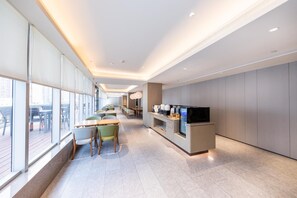 A modern hotel lobby with a long reception desk, seating area, and large windows. - Ji Hotel (nanjing Xinjiekou Central Shopping Cente (Nanjing)