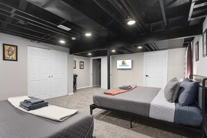 Ein Schlafzimmer mit zwei Betten, einem Fernseher und einer Tür zu einem weiteren Raum.