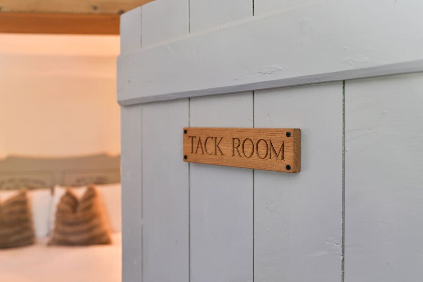 Une pancarte en bois portant l’inscription « SALLE À SELLE » est fixée à un mur blanc.