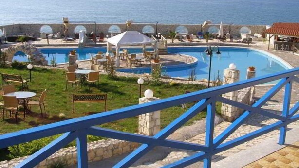 A pool area with lounge chairs and umbrellas, a white gazebo, and a view of the sea. - Lassion Beach Hotel (Sitia)