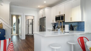 A modern kitchen with white cabinetry, stainless steel appliances, and a blue-tiled backsplash.