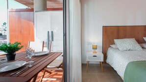 Et værelse med en seng, et sengebord med lampe, et vindue og en balkon med et bord dækket til to.