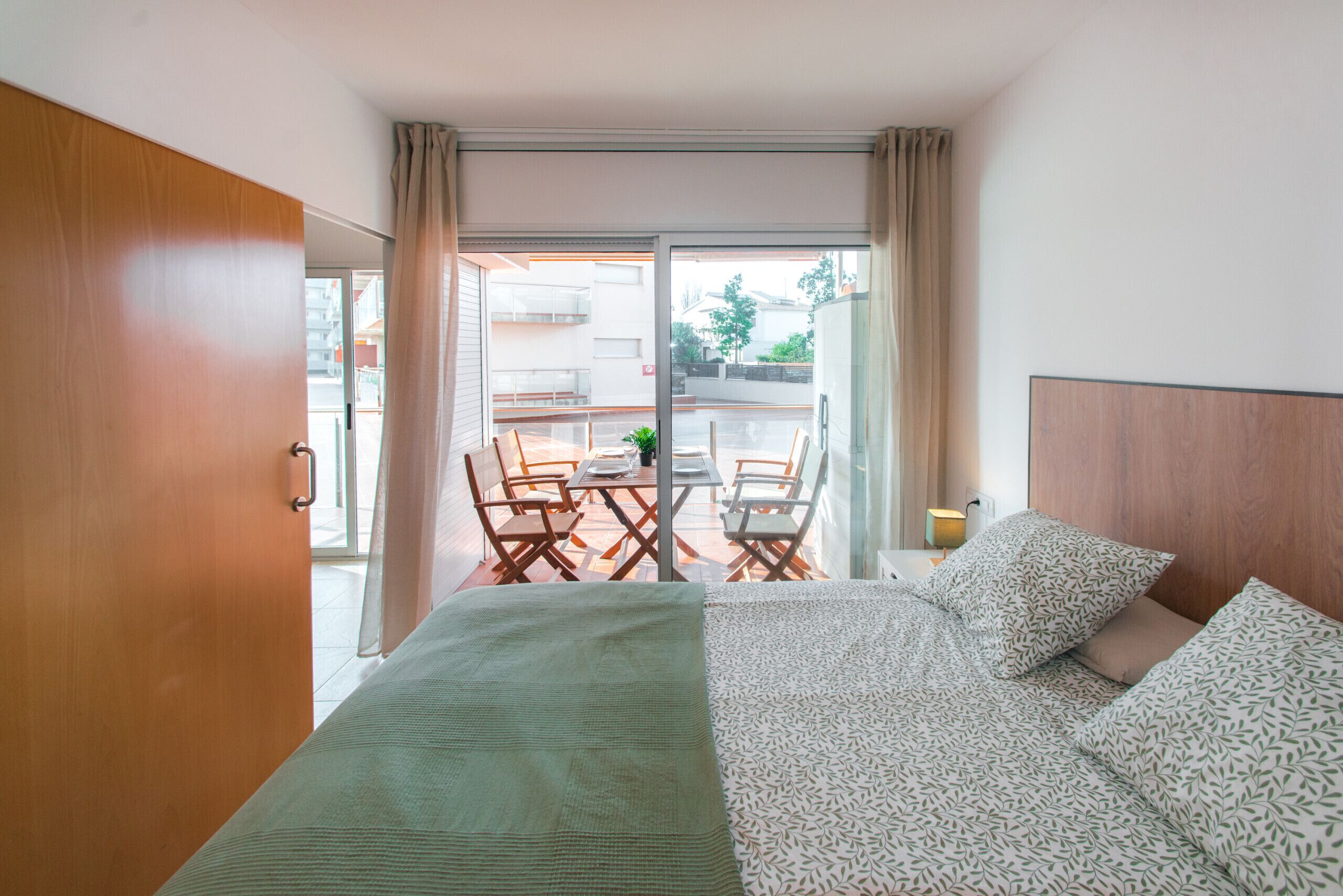 Una habitació d'hotel amb un llit, una taula amb caires i vistes a l'exterior.