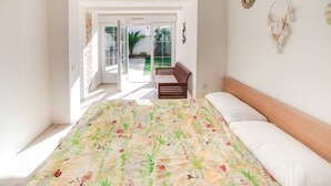 Ein Schlafzimmer mit Bett, Deckenventilator und Blick ins Freie.