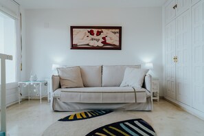 Una habitación con sofá, alfombra estampada, un cuadro en la pared y un armario.