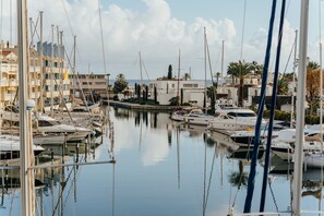 Marina con barcos amarrados, agua tranquila y edificios al fondo.
